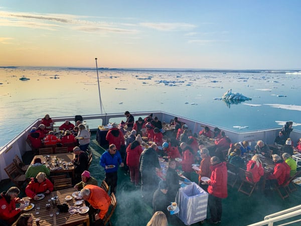 An outdoor barbeque in the Arctic aboard Expedition with guests seated at tables