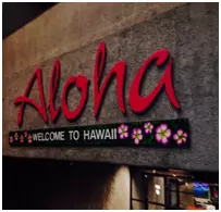 Aloha red sign that also says welcome to Hawaii with pink flowers