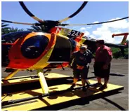 Honeymoon travelers in front of yellow and orange helicopter