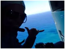 Traveler giving hang-loose sign in helicopter over water