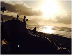 Beach goers watching the sunset on the beach in Hawaii