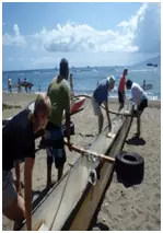 People picking up a large outrigger canoe