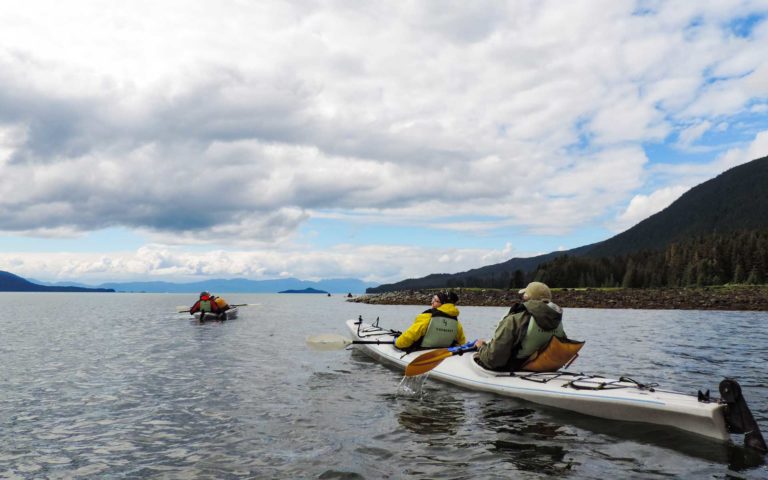 small ship cruise travelers sitting in kayaks among the san juan islands in the pacific northwest with white clouds above