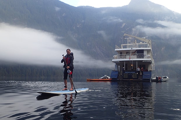 A stand-up paddle boarder floats in front of the Safari Quest on Alaska's Inside Passage & San Juans Cruise.