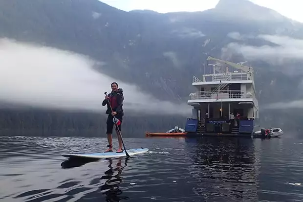 A stand-up paddle boarder floats in front of the Safari Quest on Alaska's Inside Passage & San Juans Cruise.