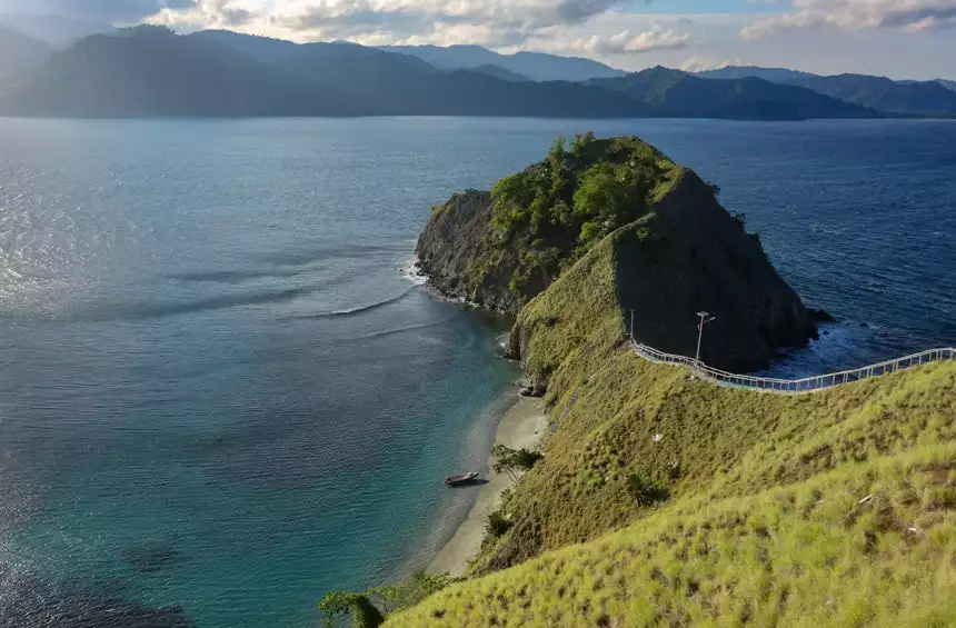 remote indonesia island with a zodiac on the beach and green hillsides