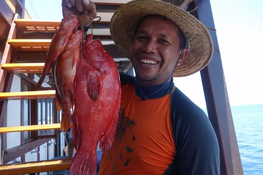 SeaTrek guide Arie poses holding up fresh red fish caught in Indonesia