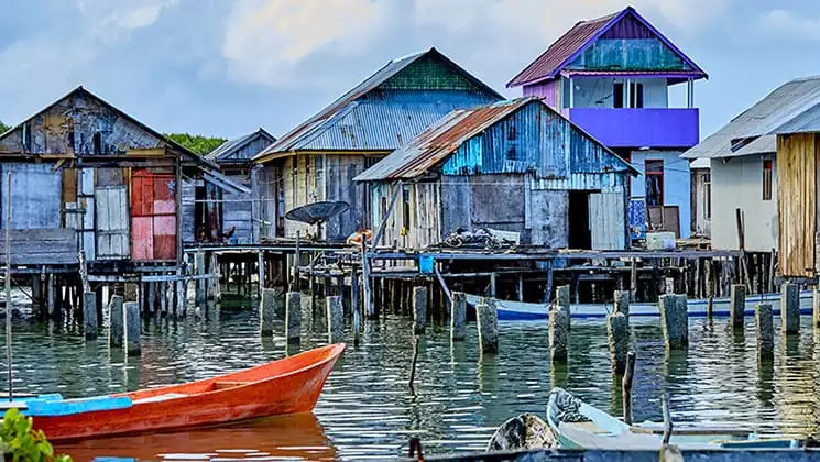 Dilapidated village painted in bright colors and standing on wooden stilts above the water in Indonesia.