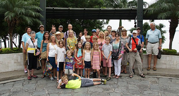 A large family reunion cruise group poses at a harbor in the Galapagos.