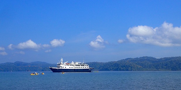 a small ship with people kayaking around it in Costa Rica