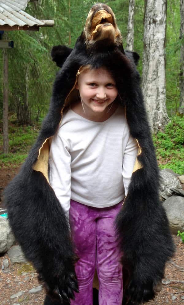 Happy small child wearing a black bear skin in Alaska.