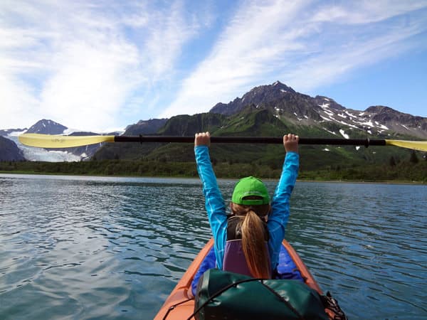 Kayaker holding up paddle while kayaking on Shilak Lake.