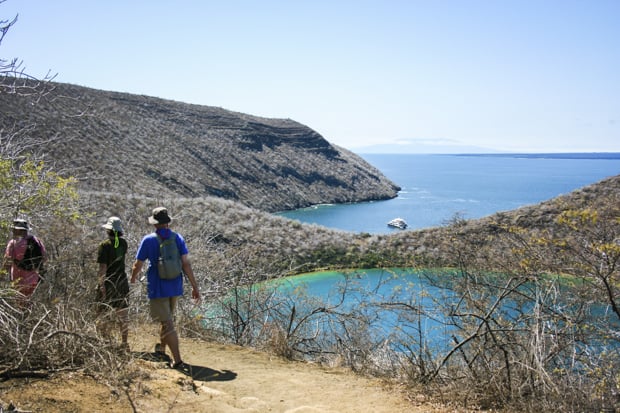 Guests on land excursion in front of small ship in bay of the Galapagos. 