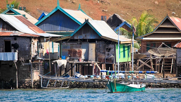 A fishing village with basic wooden homes built on stilts over the blue waters of Indonesia, visited during the Aqua Blu Indonesia cruise between Bali & Flores, to Komodo National Park.