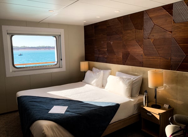 Inside of the Coral Adventurer wooden walls with artistic pattern horizontal, window opening to the teal ocean