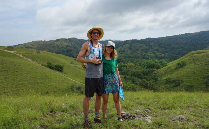 a couple hug and pose for a photo in the green lush mountains of Indonesia, a shore excursion on their remote Sulawesi cruise 