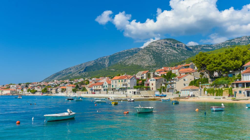 Seaside town of Brac with small fishing boats, white-sand beach & terra cotta-roofed homes, seen during the Best of Croatia luxury cruise.
