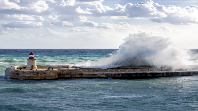 A large wave slams into a sea wall on a partly sunny day in the Mediterranean during the Best of Croatia Cruise.