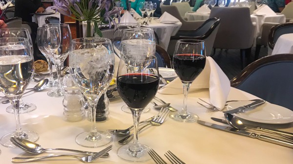 a table with white table cloth and red wine glasses at the restaurant aboard hebridean sky polar expedition ship  