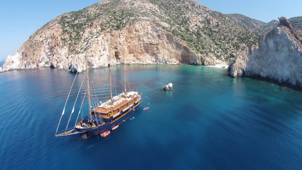 Large yacht charter Galileo seen from above near a rocky shoreline in Greece