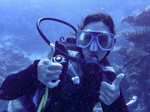 Woman SCUBA diving with two thumbs up in the Great Barrier Reef