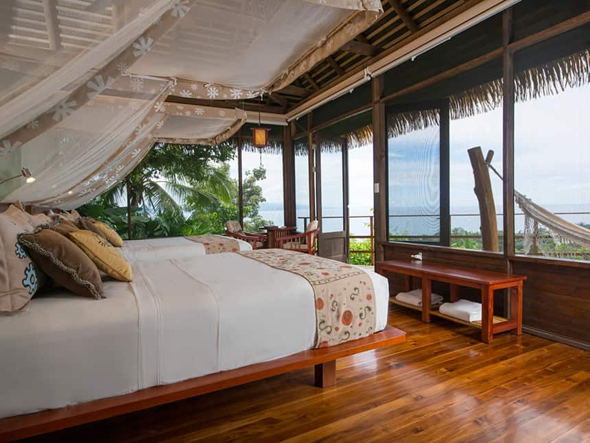 a cabana room with a king side bed and bug net, panoramic wrap around windows and a hammock at the Lapa Rios Eco Lodge Costa Rica,
