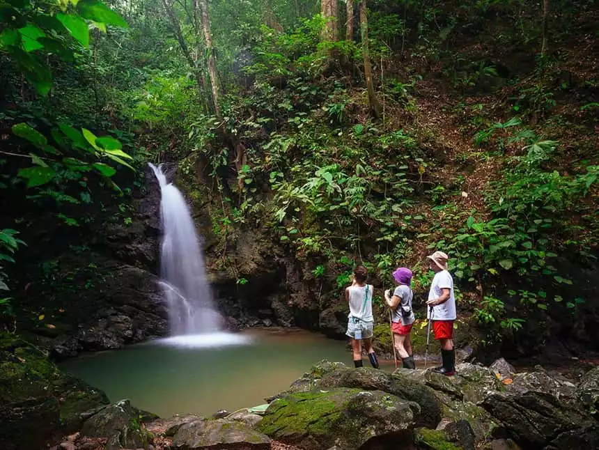 three travelers stand infront of a waterfall in the costa trican jounge at the Lapa Rios Eco Lodge