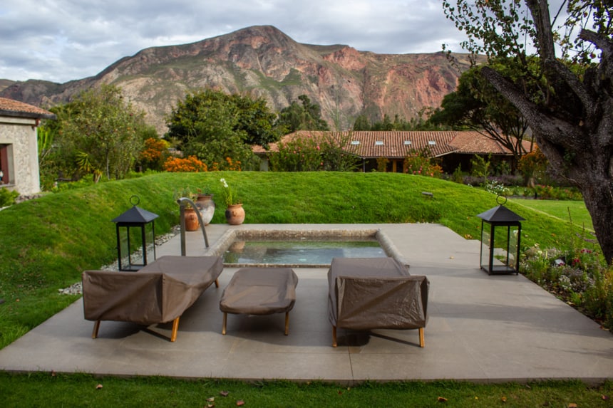 outdoor jaccuzi area at Sol Y Luyna, a Sacred Valley Peru Lodge, surrounded by grass and a jagged mountain range