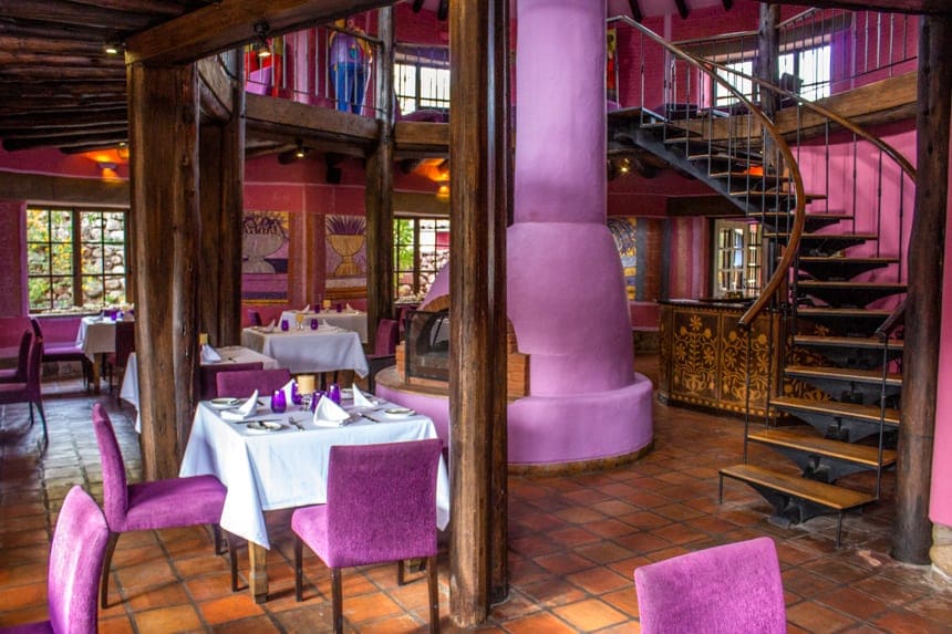 bright purple walls, chairs and fireplace decorate the inside dinning area of Sol Y Luna, a lodge in the Sacred Valley of Peru