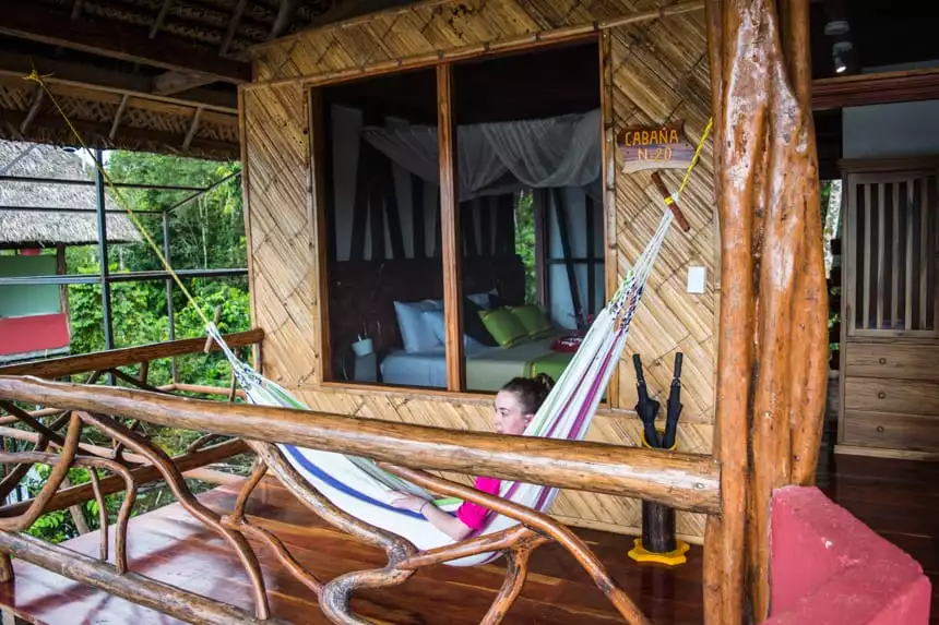 a traveler lays in a hammock on her front porch of a cabana at Napo Wildlife Center in the Ecuadorian Amazon
