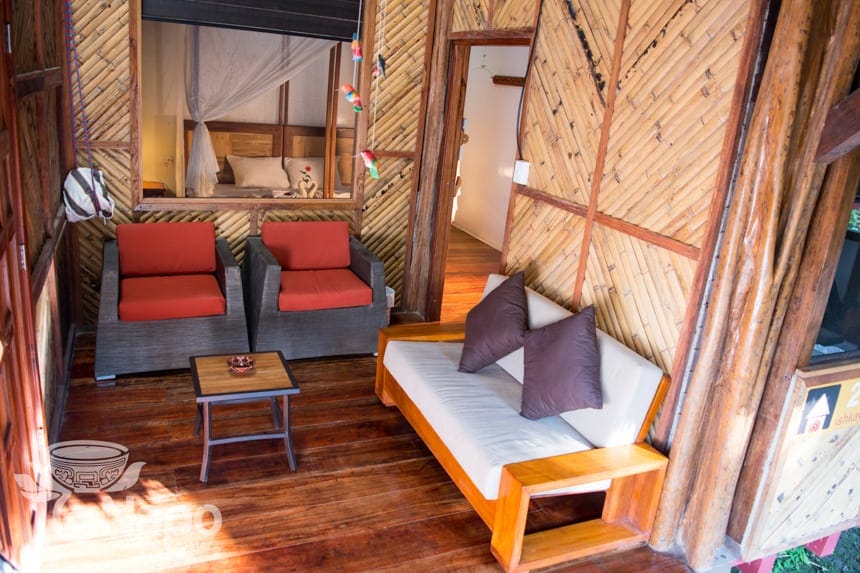a second lounge area in a suite at the Napo Wildlife Center, two red accent chairs and a love seat sit inside a bamboo walled room.