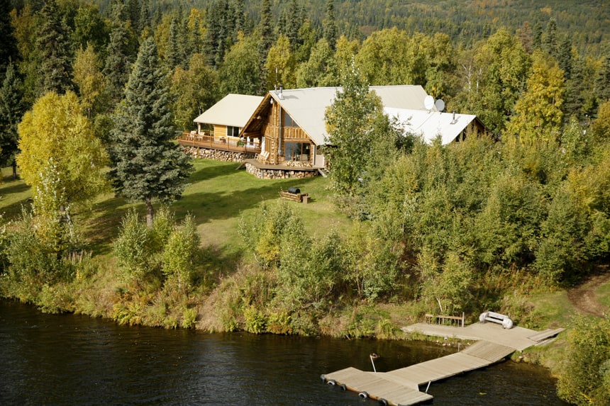 An areal view of the Winterlake Lodge, surrounded with lush green forest, with a dock on the lake