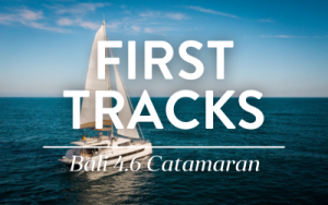Belize charter yacht First Tracks, a 46-foot while catamaran, sits in calm water with both sails fully open.