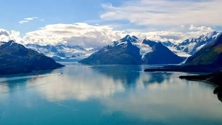 Areal view of Prince William Sound in Alaska, teal water surrounded by snow topped mountain range