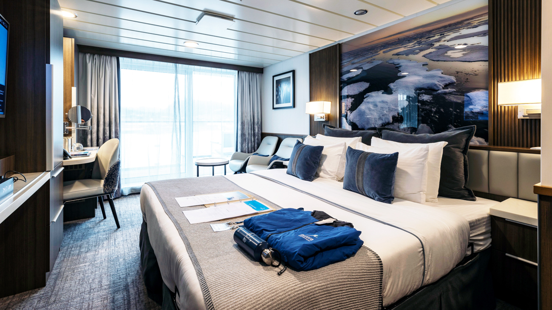 While cruising the polar waters stay warm and comfortable in the Category A Balcony Stateroom aboard the Sylvia Earle with large plush beds