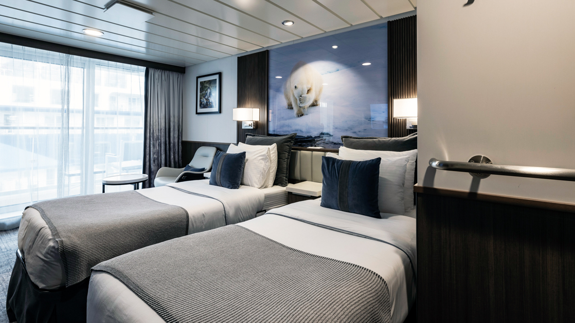 While cruising the polar waters stay warm and comfortable in the Category C Balcony Stateroom aboard the Sylvia Earle with large plush beds