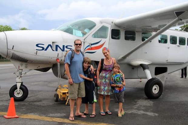 A family of travelers in front of a Costa Rican plane.