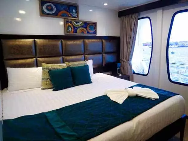 Inside view of a stateroom on the Alya of a king size bed and large panoramic windows.