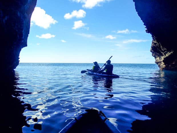 Couple kayaking through a large cave off the Galapagos Islands.
