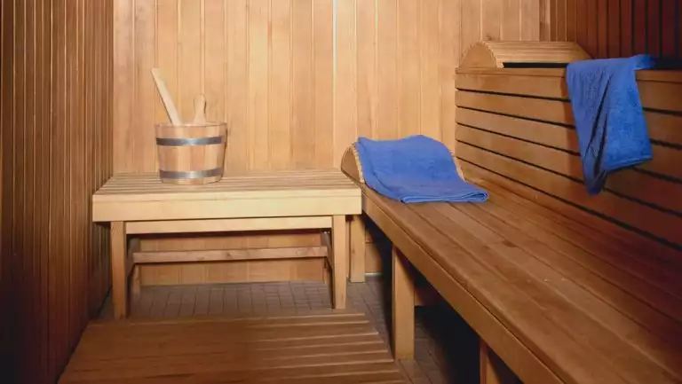 Wooden sauna with water pail, headrests & blue towels aboard all-inclusive ship Seaventure.