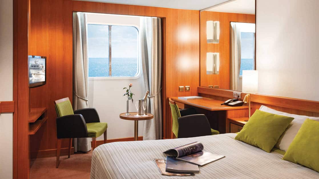 Window Stateroom aboard Seaventure polar ship, with queen bed, desk, TV & view window.
