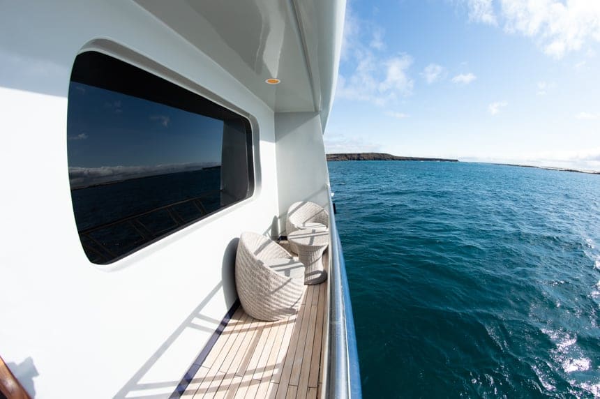 The private balcony of cabin 4 aboard the Camila Galapagos trimaran - teo chairs and a small round coffee table look out over the ocean