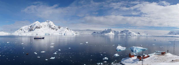 Panorama of small ship cruise in Antarctica with research station. 