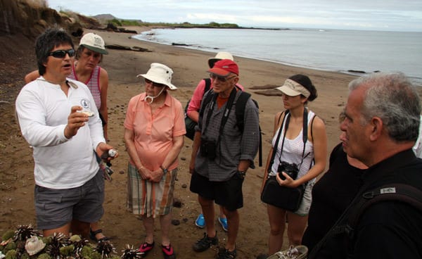Galapagos travelers with a naturalist looking at tidal creatures.