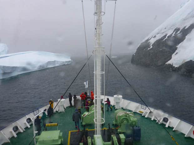Bow of a small ship cruise going through a narrow channel in Antarctica. 