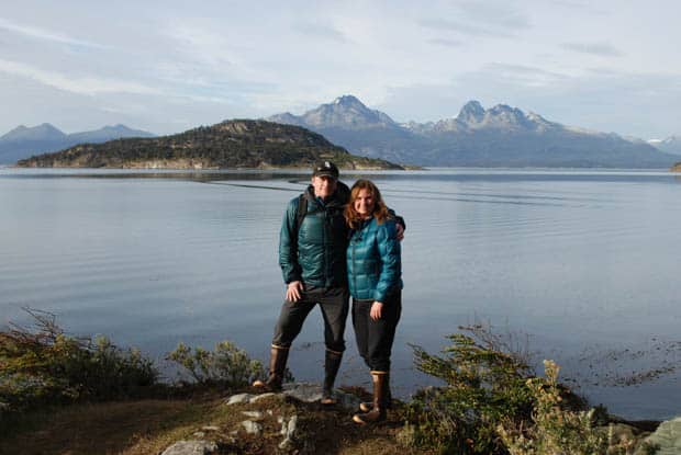 Two people smiling in Tierra del Fuego National Park with mountains in the background. 