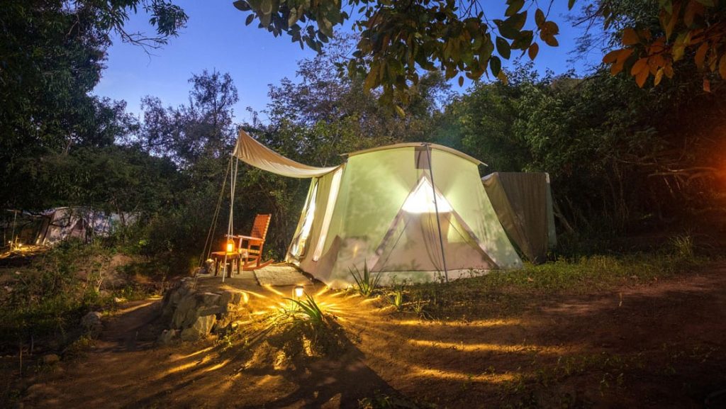 Exterior of Baja glamping tent lit up by lanterns at night.