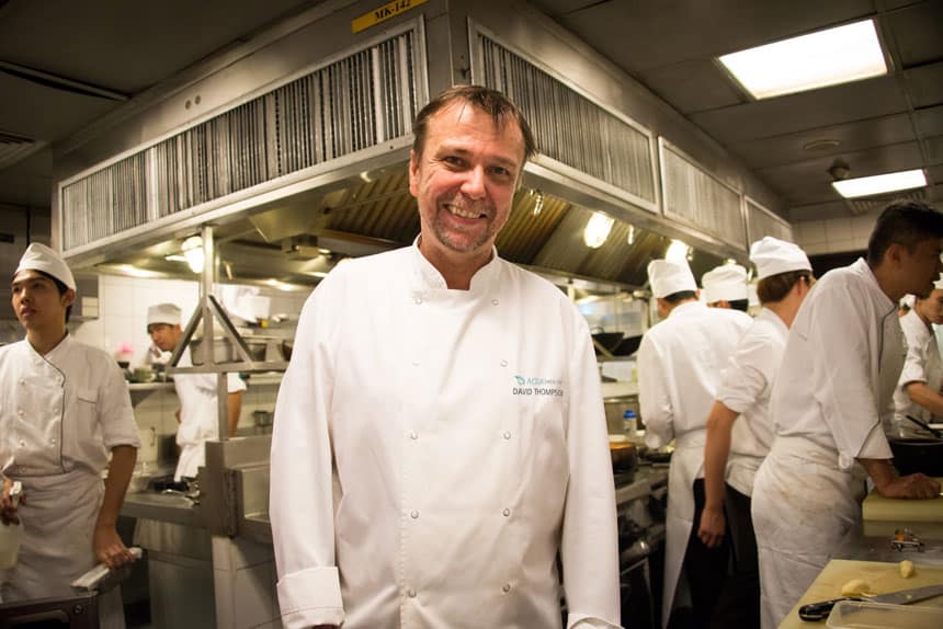 Chef David Thompson smiling in the kitchen of the Aqua Mekong riverboat as his staff cooks around him.