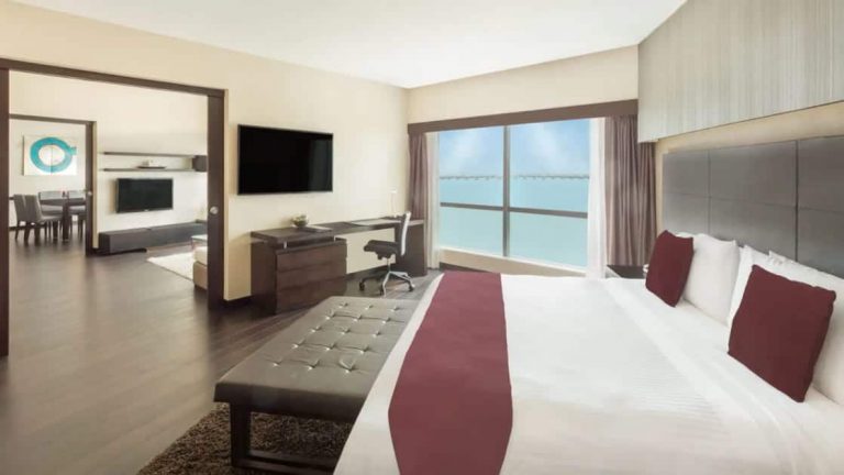 Presidential Suite bedroom at Wyndham Guayaquil Hotel with double bed, flat-screen TV, large windows & desk.