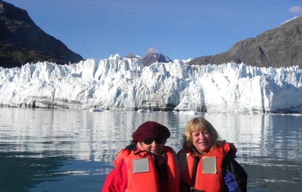 2 small ship travelers in front of Grand Pacific glacier in Glacier Bay National Park.